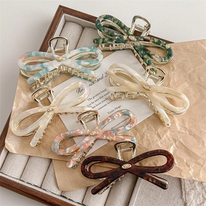 Elegant bow-shaped acetate claw clips in six colors with gold metal frame