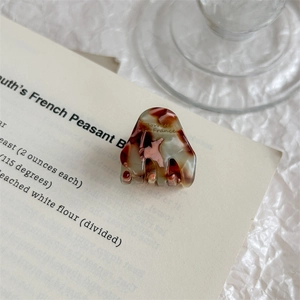 Close-up of tortoise shell acetate hair claw clip with gold logo on vintage book