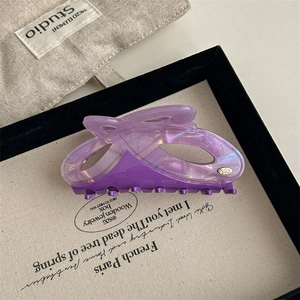 Macro shot of large acetate shark hair claw clip in iridescent purple with YD logo
