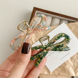 Retro acetate bow hair claw clip with marble texture and gold logo in two colors