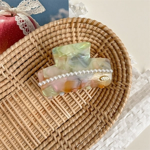 Detail of elegant acetate claw clip with marble texture and white pearl embellishments