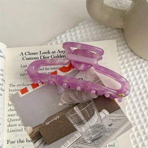 Macro detail of purple marble acetate hair claw clip with golden logo accent