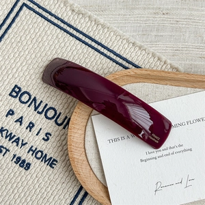 Detail view of burgundy cellulose acetate hair clip with gold handmade inscription
