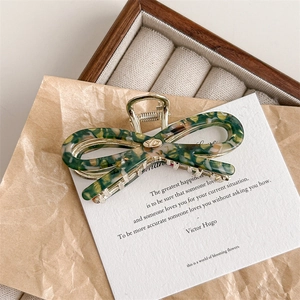 Detail view of green marble pattern resin bow hair claw with gold metal frame