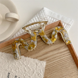 Close-up of a 14cm wavy marble hair claw clip on a wooden tray with French style decor