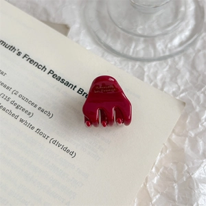 Close-up of a glossy burgundy acetic acid hair clip with gold lettering on a book
