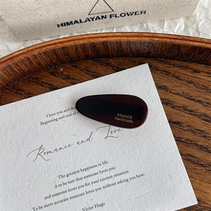 Detail view of acetate teardrop hair clip featuring gold France Handmade lettering