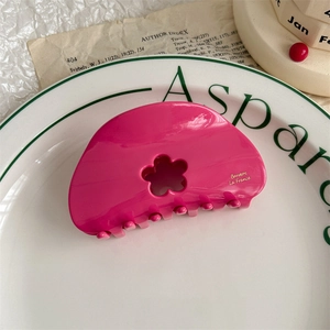 Detail of hot pink flower hair claw with gold lettering in a decorative ceramic bowl