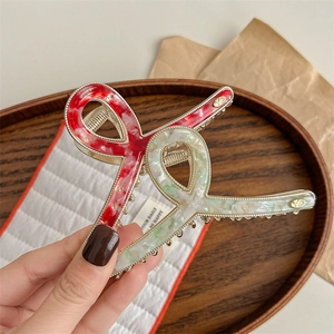 Golden metal hair claw clip with tricolor marble acetate bow and YD logo detail