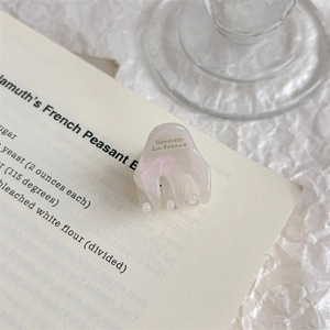 Detail of elegant pearl white acetate hair claw clip with golden French lettering