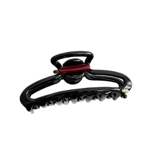 Minimalist black resin shark hair claw clip with red stripe detail and golden logo