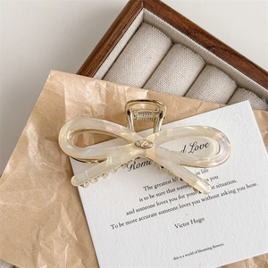 Detail of elegant acetate bow hair claw with pearlescent finish and gold metal accents