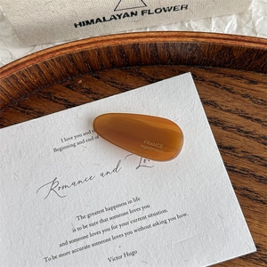 Close-up of amber acetate water-drop hair clip with France Handmade text engraving