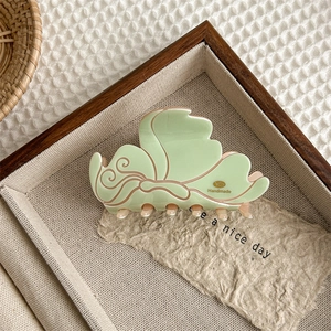 Detail einer handgefertigten Schmetterling Haarklammer aus grün-beigem Acetat Stoff