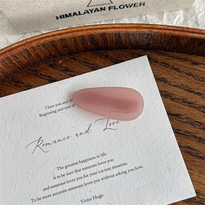 Detailed close-up of a pink matte acetate water drop hair clip with handmade gold lettering