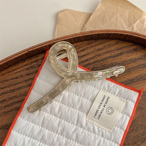 Detail of elegant marbled acrylic hair claw clip with golden metal frame and sturdy spring