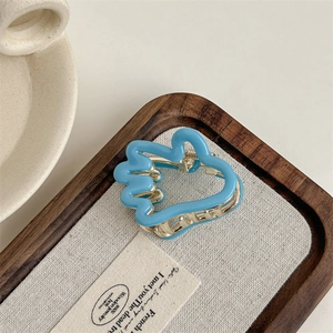 Détail de la pince à cheveux bleu clair en forme de palmier sur plateau en bois et lin