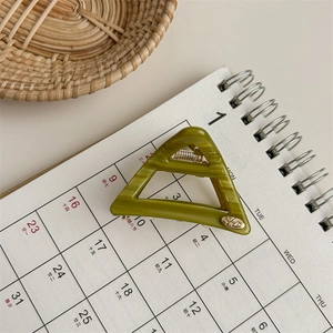 Detail of green triangle acetate hair claw clip with marble texture on calendar