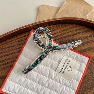 Close-up of marble pattern hair claw clip with golden metal frame on wooden tray
