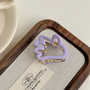 Détail d'une pince à cheveux violette ondulée avec mécanisme en métal doré sur tissu