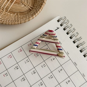 Detail of triangle acetate hair claw with colorful ice cream stripes and gold logo