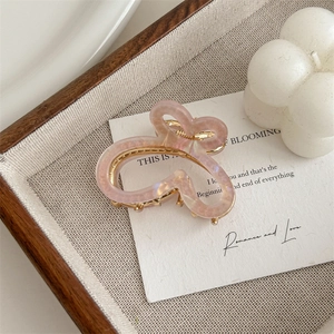 Detail of a pink gradient butterfly hair claw clip with pearls on a wooden tray