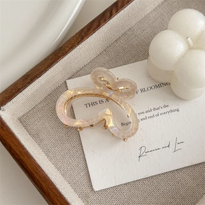 Detail of a gradient pearlescent butterfly hair claw clip with golden metal base on tray