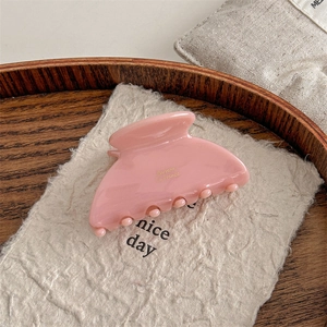 Macro detail of pink cellulose acetate hair claw with gold Barrette La France lettering