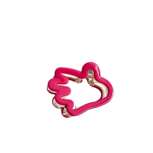 Mini pince à cheveux rose vif en forme de main avec base en métal doré sur fond blanc