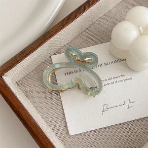 Detail of butterfly hair claw with pearlescent gradient green finish and gold spring