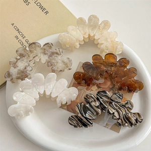 Large petal hair claws in five marble textures displayed on a white ceramic plate
