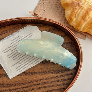 Detail of large marble blue hair claw clip with glitter on elegant wooden tray