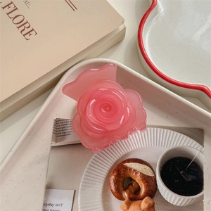 Détail d'une pince à cheveux rose en forme de rose avec un design en résine translucide