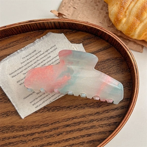 Macro detail of large marble acetate hair claw with pink blue gradient and gold glitters