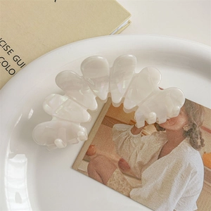 Detailed close-up of iridescent pearl white wavy hair claw clip on elegant ceramic plate
