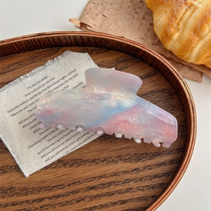 Detail of gradient pink and blue marble hair claw clip on elegant fabric background