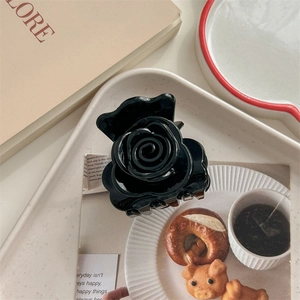 Détail d'une pince à cheveux rose noire brillante posée sur un plateau décoratif