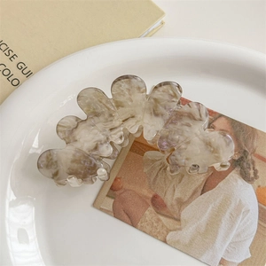 Detail of large acetate hair claw clip with marble texture on a ceramic plate