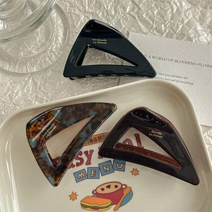Three minimalist triangular acetate claw clips in black, tortoiseshell, and brown colors