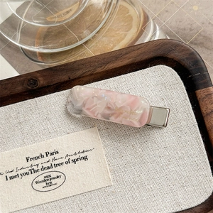 Detailed macro view of pink marble acetate hair clip with silver metal grip