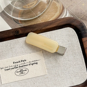Macro shot of French acetate barrette in cream yellow with metal clip and engraving