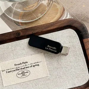 Detail of vintage black hair clip with gold lettering on a wooden tray background
