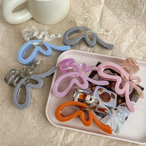 Elegant butterfly hair claws in various colors and patterns displayed on a pink tray