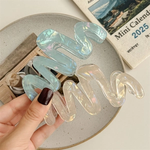 Iridescent wave-shaped hair claws in pastel blue and champagne for summer styling