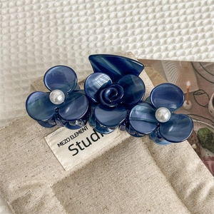 Detailed macro view of navy blue cellulose acetate hair claw with delicate pearl flowers