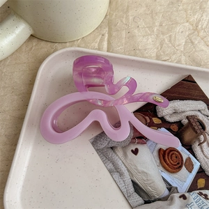 Detailed close-up of butterfly hair claw clip in purple acetate with metallic gold logo