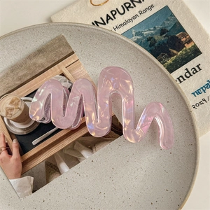 Close-up of a pearlescent pink wavy hair claw clip on a stylish decorative tray