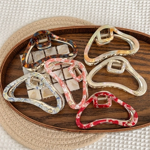Hollow triangular acetate hair claws in assorted patterns including marble and tortoiseshell