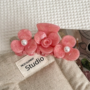 Close-up of pink acetic acid floral hair claw clip with pearls and marble texture