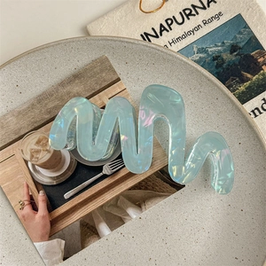 Close-up of a large wave-shaped hair claw clip in iridescent pearly light blue finish